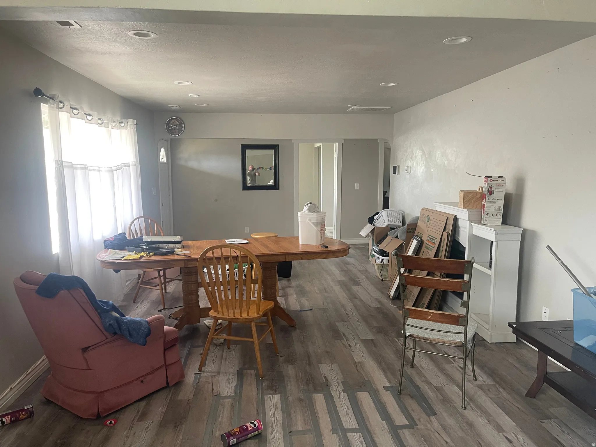 Open-concept living area featuring wood-finish flooring, recessed lighting, and ample natural light from a window with white curtains