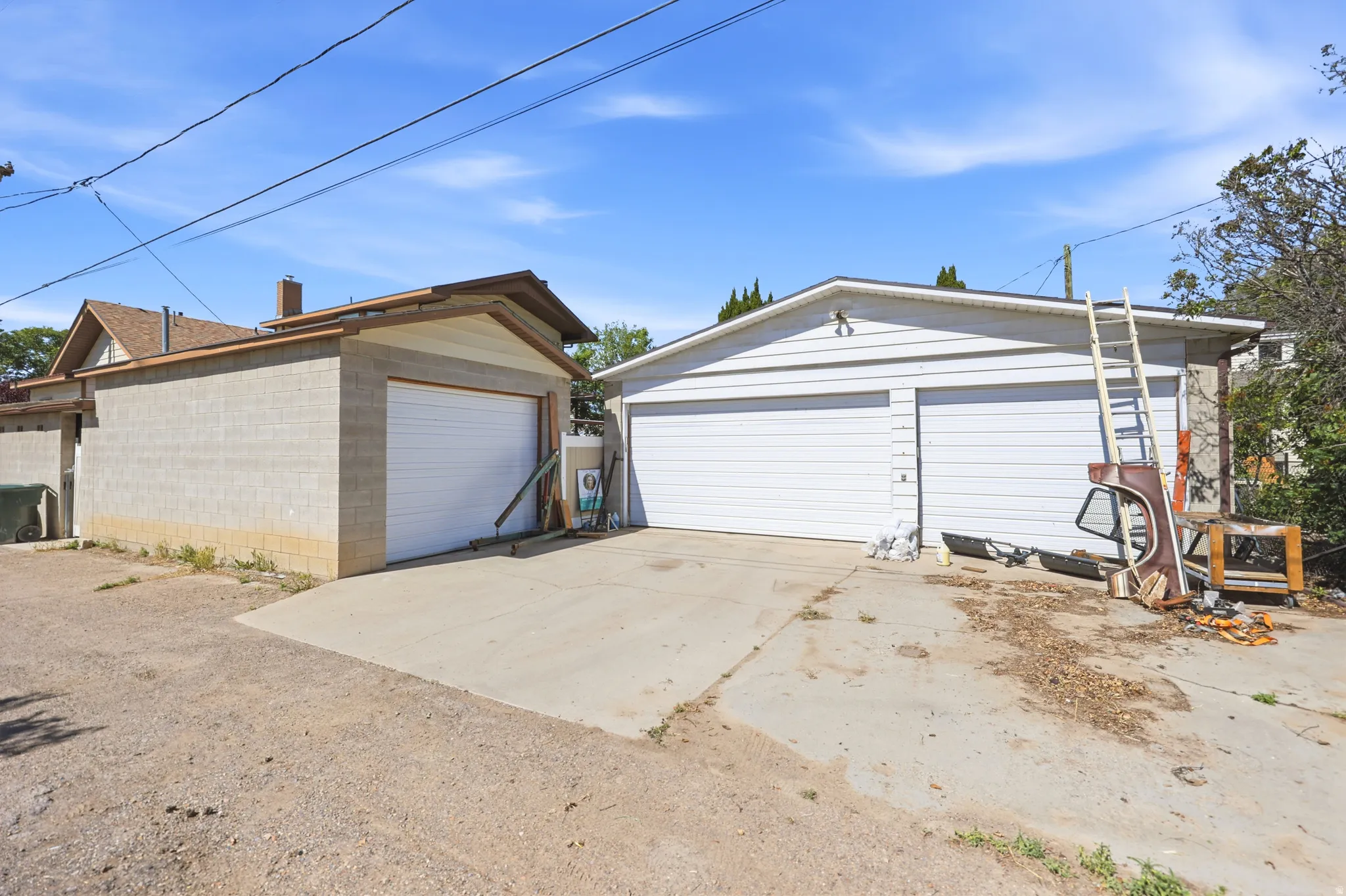 Two detached garages offering multiple vehicle storage, featuring a concrete block structure with a single garage door and a white siding structure with two garage doors