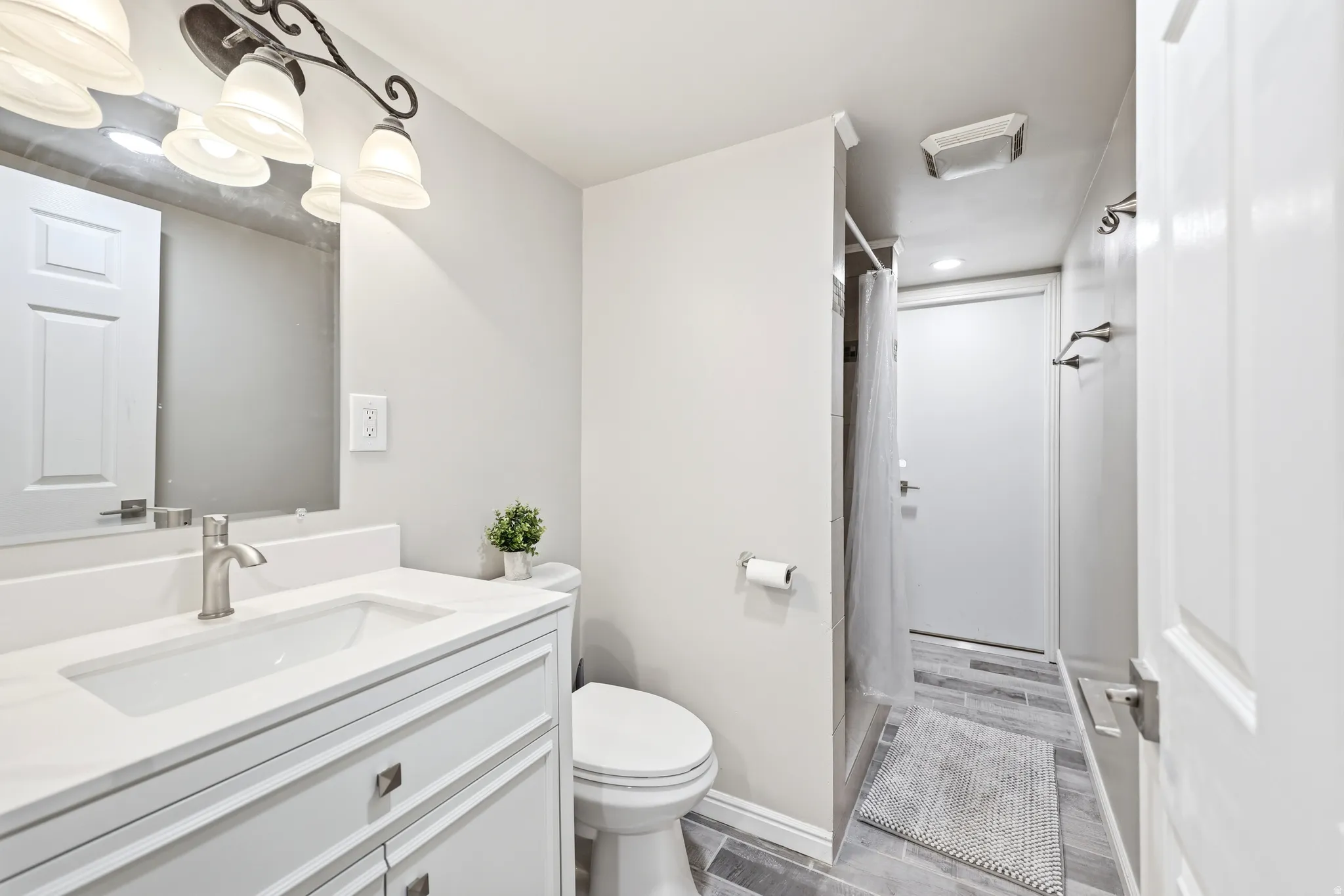 Bathroom featuring a single-sink vanity with white cabinetry, a rectangular undermount sink, and a brushed nickel faucet
