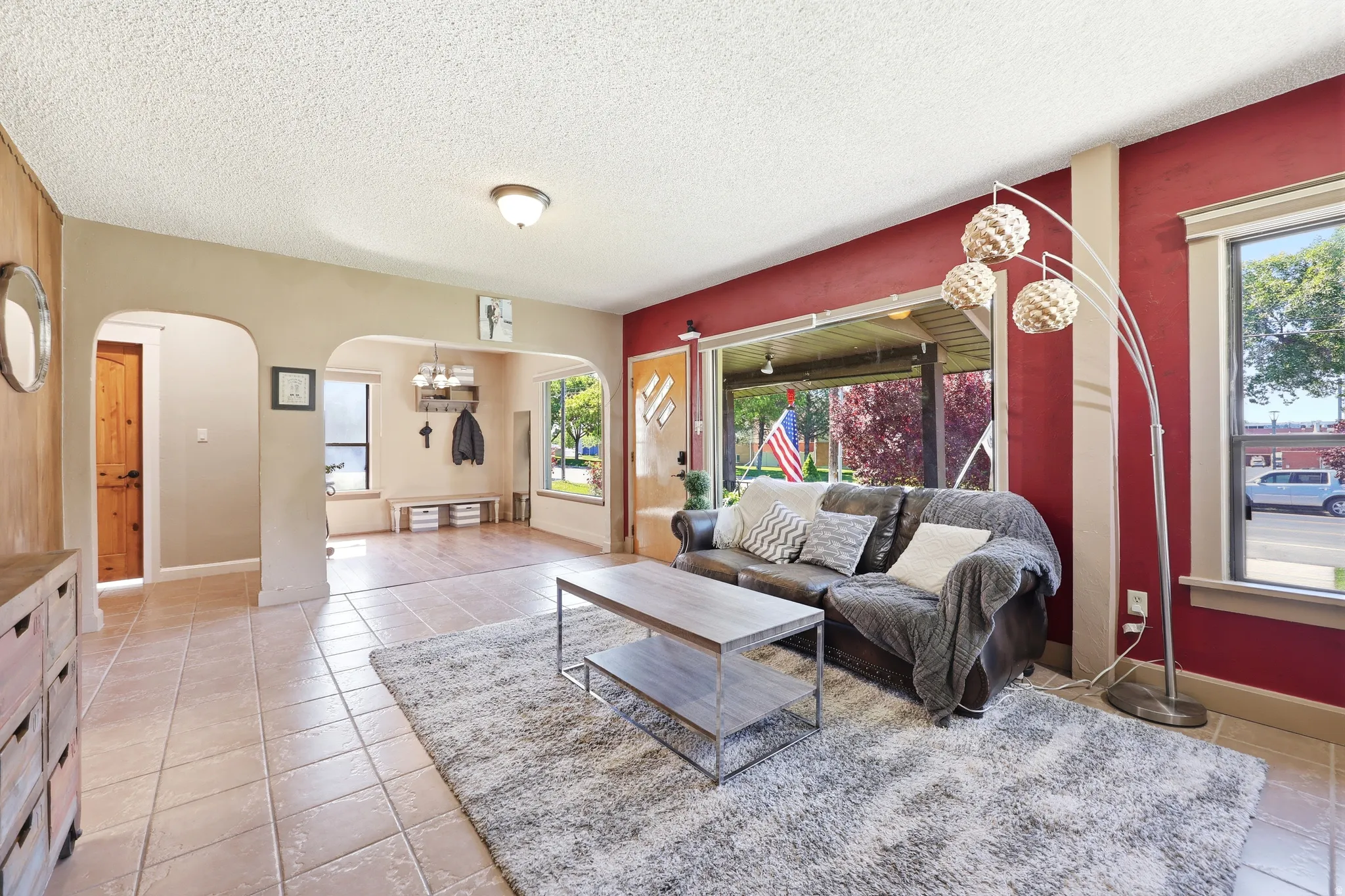 Living area featuring ceramic tile flooring, arched doorways, a built-in bench, and large windows