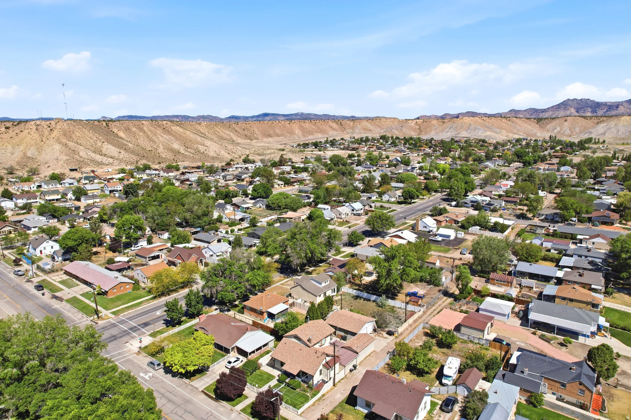 Aerial perspective showcasing a residential area with mature trees and paved streets, framed by distant arid mountains