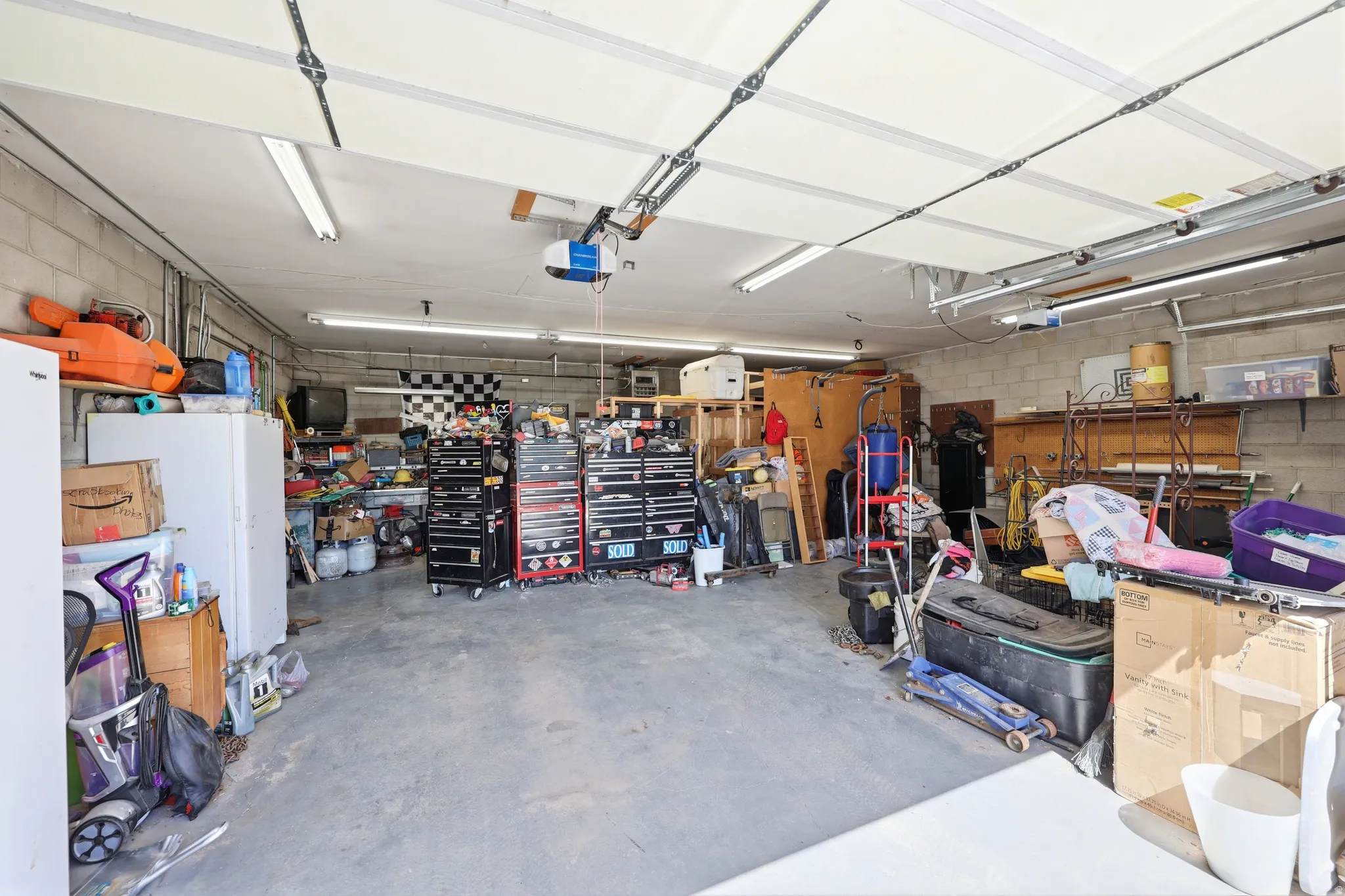 Spacious garage featuring a concrete floor, block wall construction, overhead lighting, and an automatic garage door opener