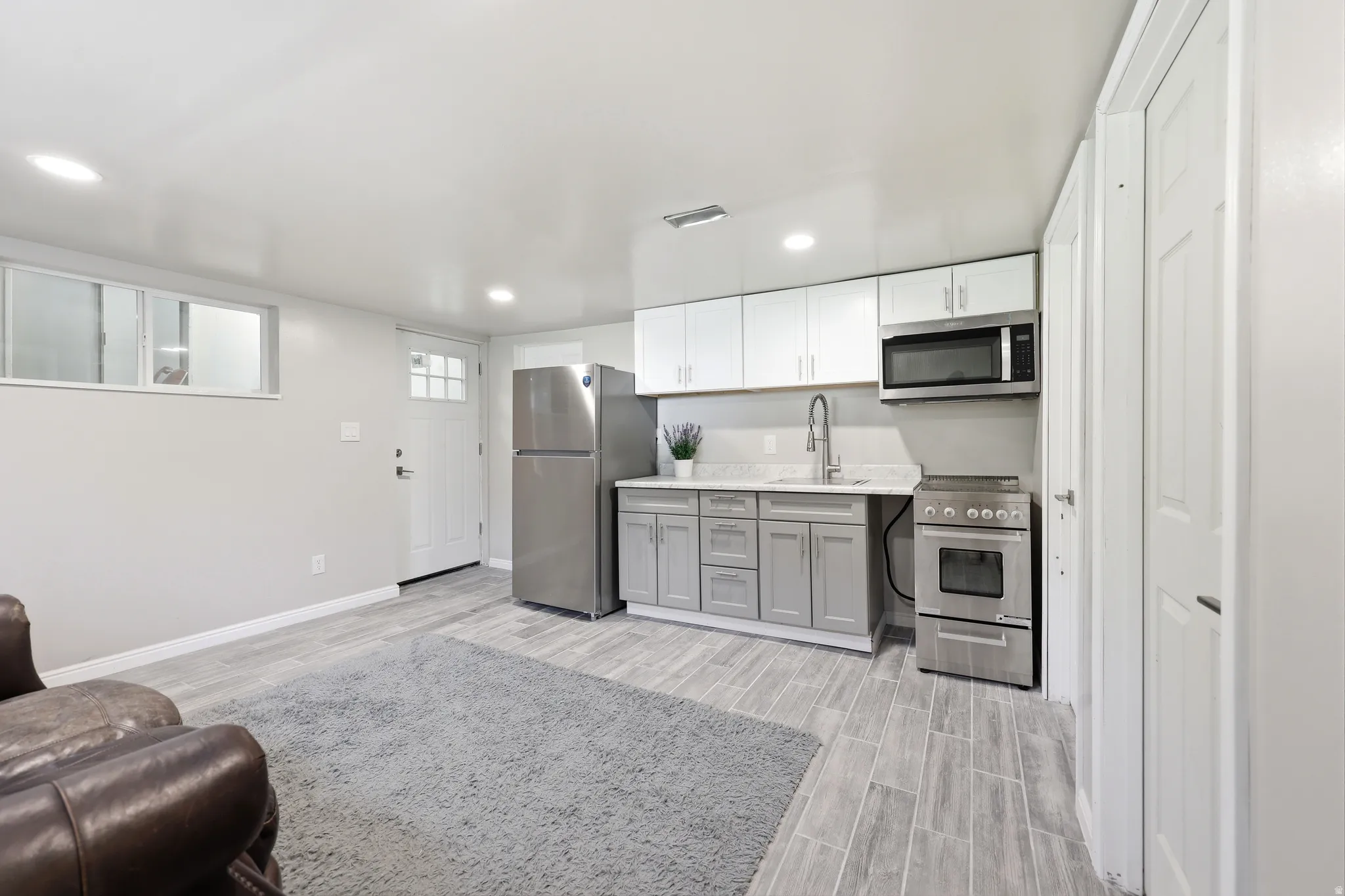 Open-concept living space featuring wood-finish flooring, a full kitchen with stainless steel appliances, two-tone cabinetry, and recessed lighting