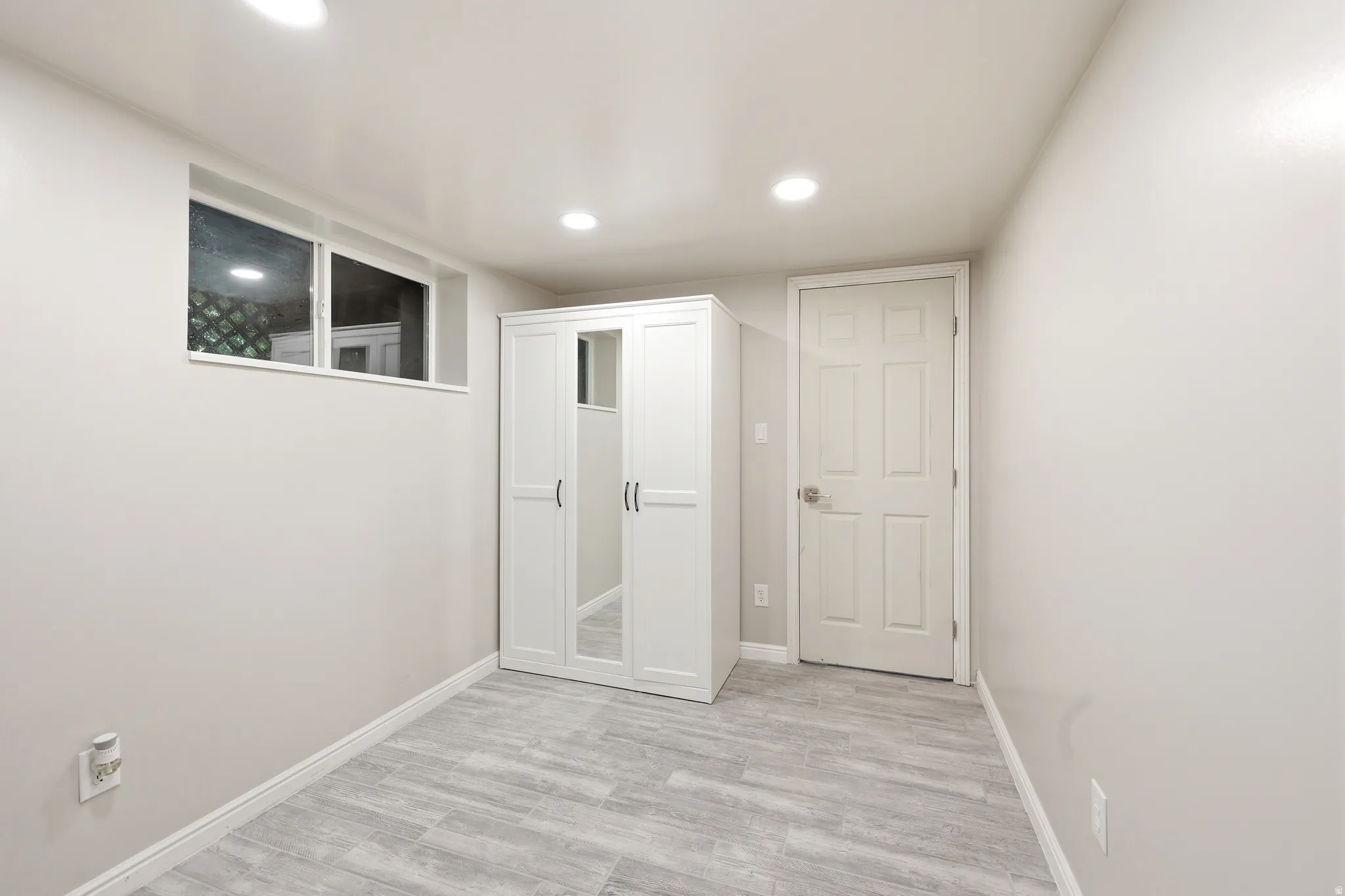 Room featuring light grey walls, recessed lighting, and wood-finish flooring