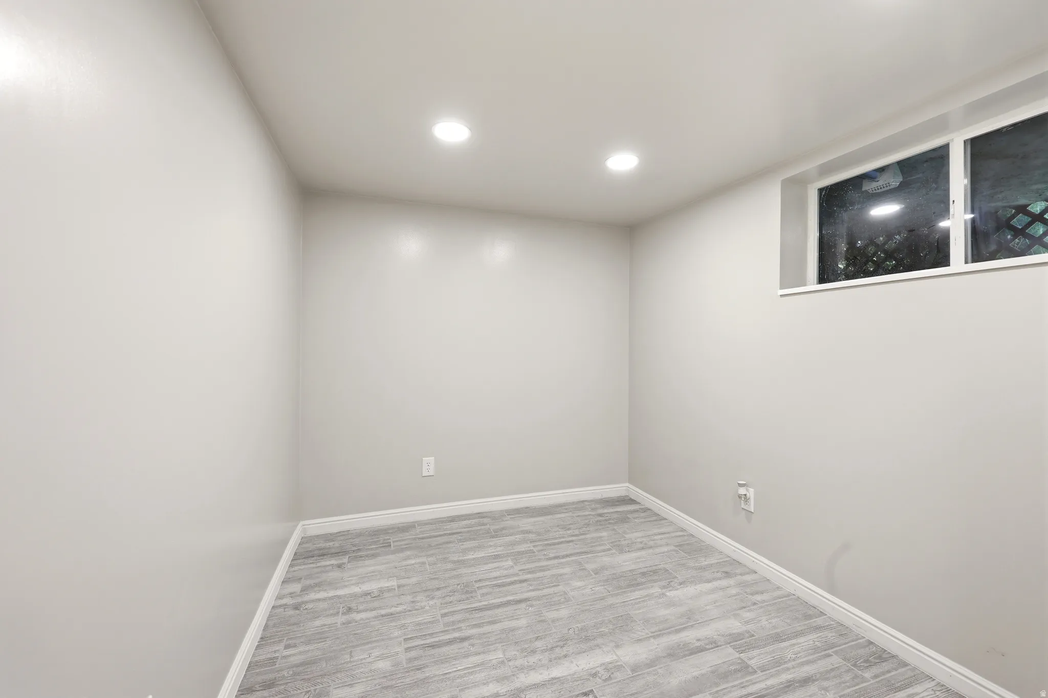 Spacious room featuring light gray walls, recessed lighting, and wood-finish tile flooring