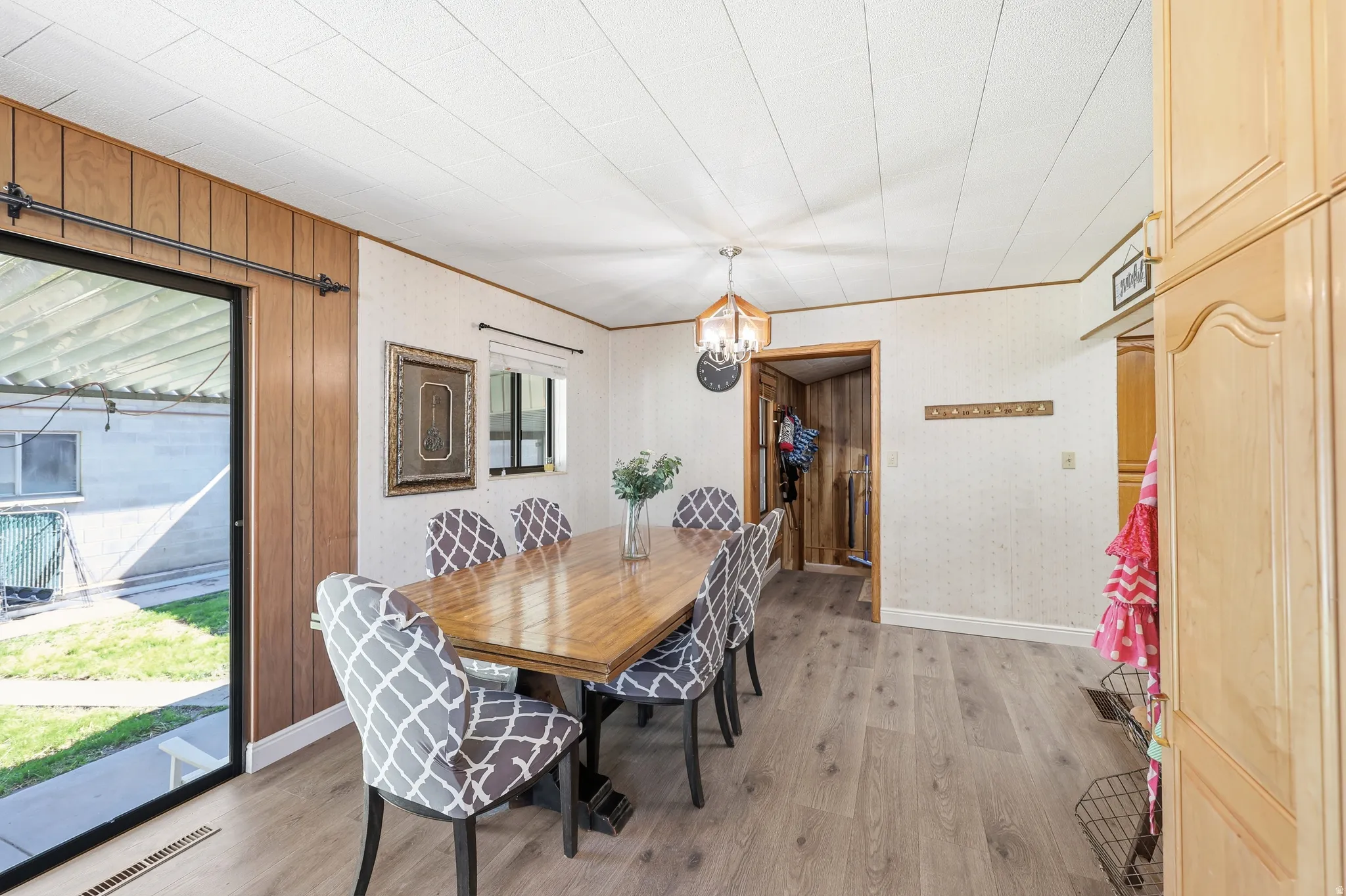 Dining area featuring light wood-finish flooring, a contemporary chandelier, and built-in cabinetry with arched panels