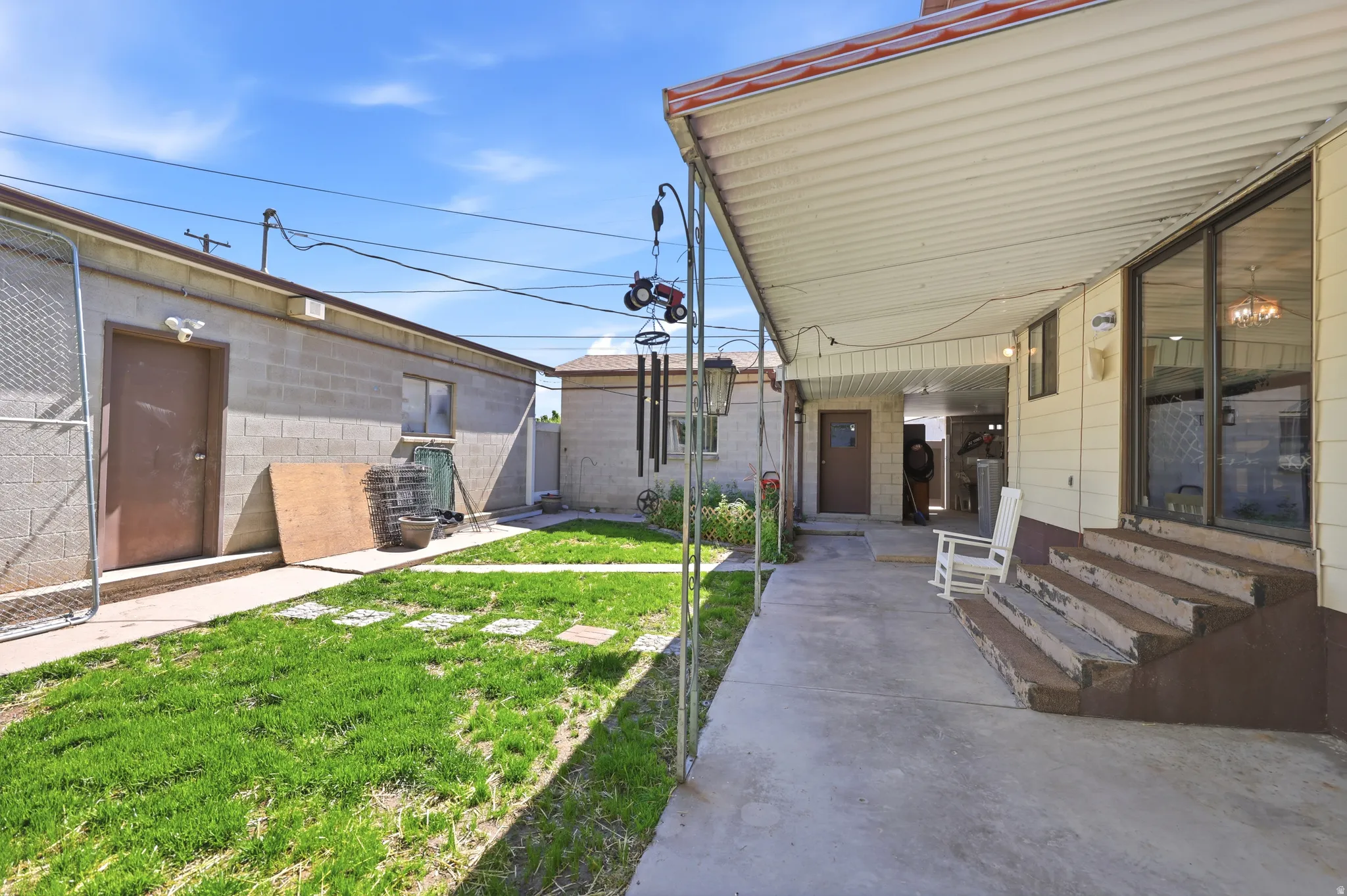 Expansive concrete patio with a full-length overhead cover and steps leading to large sliding glass doors