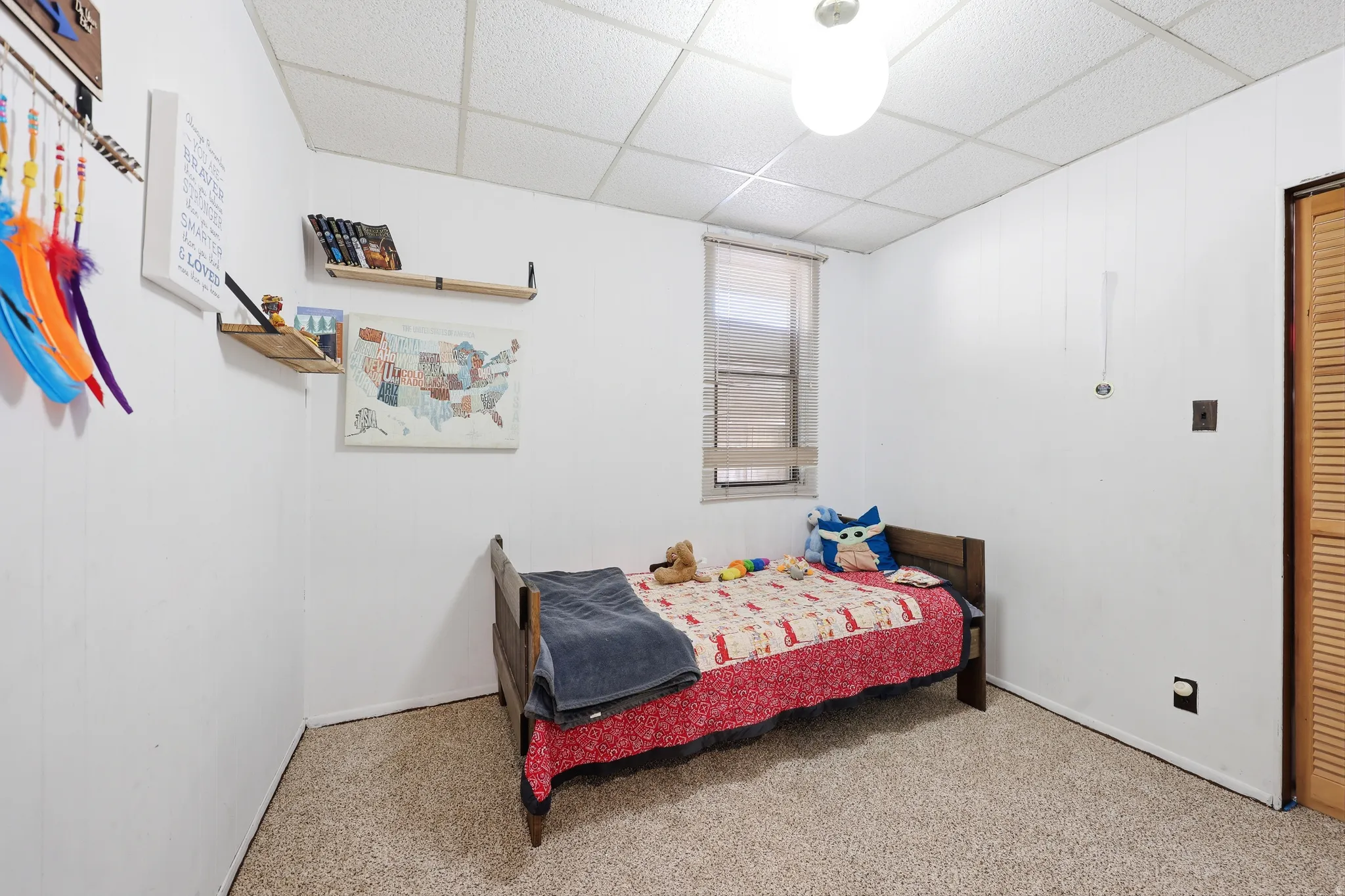 Carpeted room with white paneling, a single window, and a louvered bi-fold door
