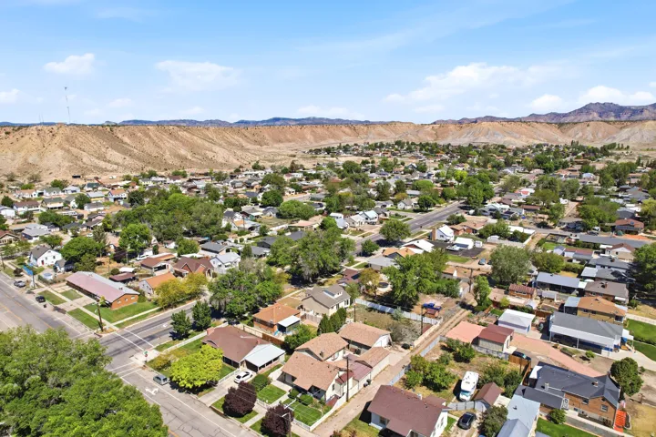 Aerial perspective showcasing a residential area with mature trees and paved streets, framed by distant arid mountains