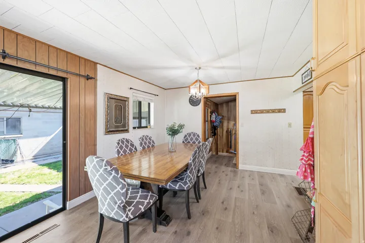 Dining area featuring light wood-finish flooring, a contemporary chandelier, and built-in cabinetry with arched panels