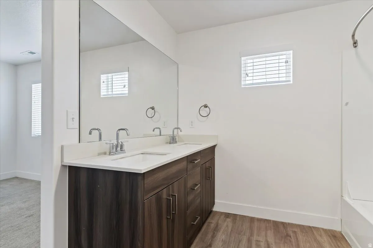 Double vanity with light-toned countertop, dual sinks, and chrome faucets