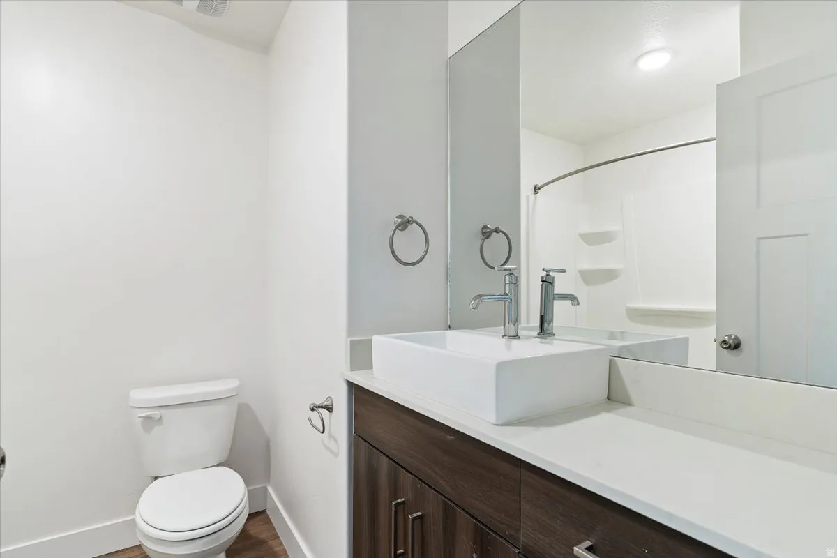 Contemporary bathroom featuring a vessel sink, chrome fixtures, dark wood-finish cabinetry, a white countertop, and a shower/tub combination with a curved rod
