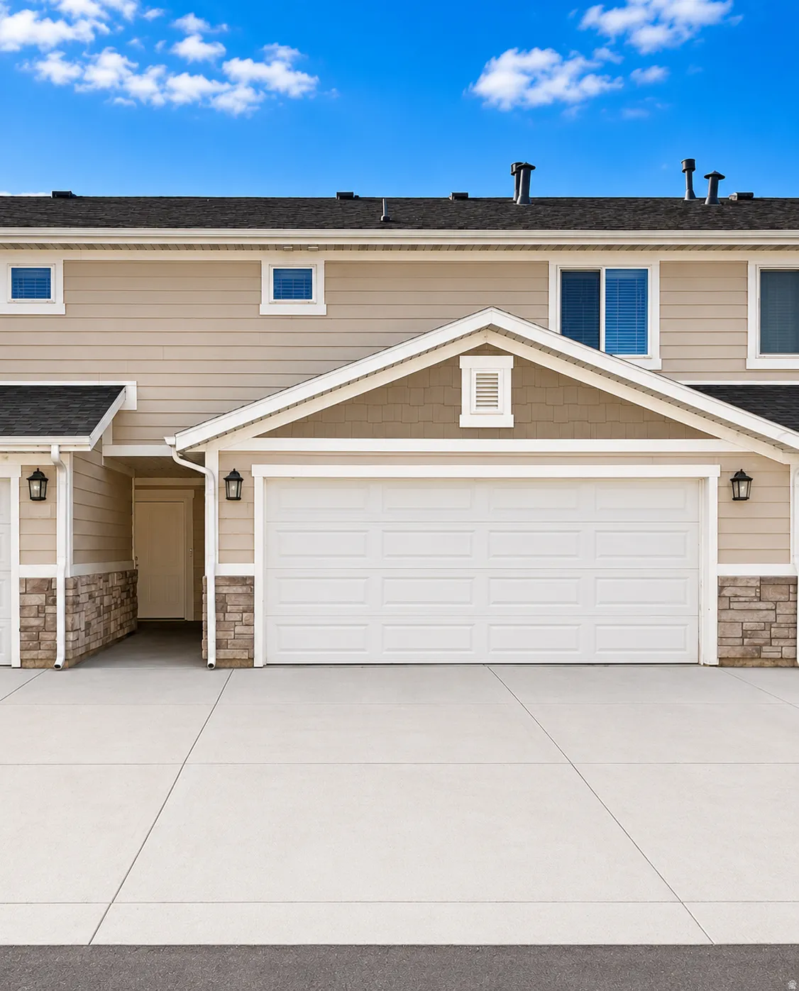 Exterior featuring a two-car garage with a panel door, concrete driveway, stone veneer accents, and horizontal siding