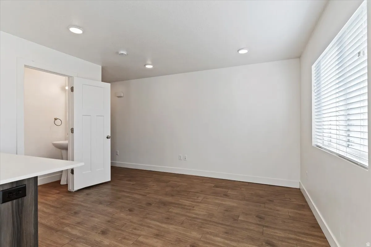 Spacious interior featuring wood-finish flooring, recessed lighting, and a window with horizontal blinds