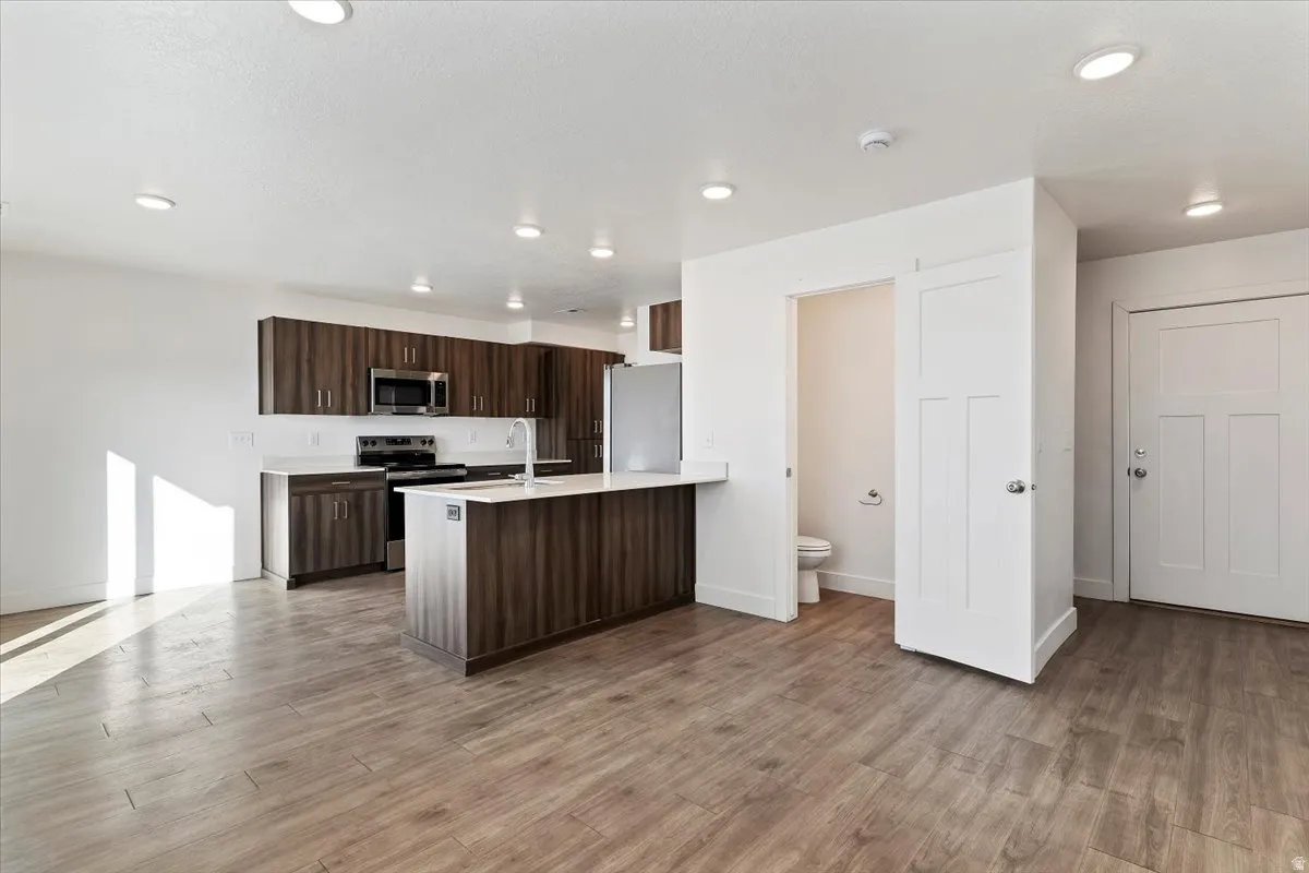 Open-concept kitchen and living area featuring wood-finish flooring, recessed lighting, and a kitchen island with seating