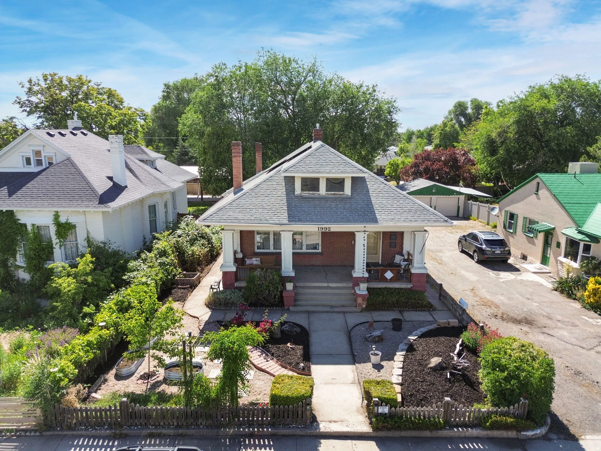 Traditional residential structure featuring a gray shingle roof and two brick chimneys