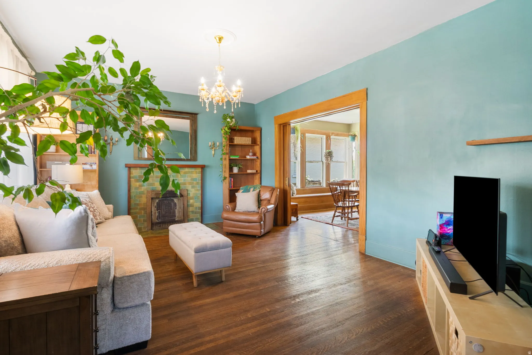 Living area featuring wood-finish flooring, a tiled fireplace with wood mantel and mirror, and built-in shelving
