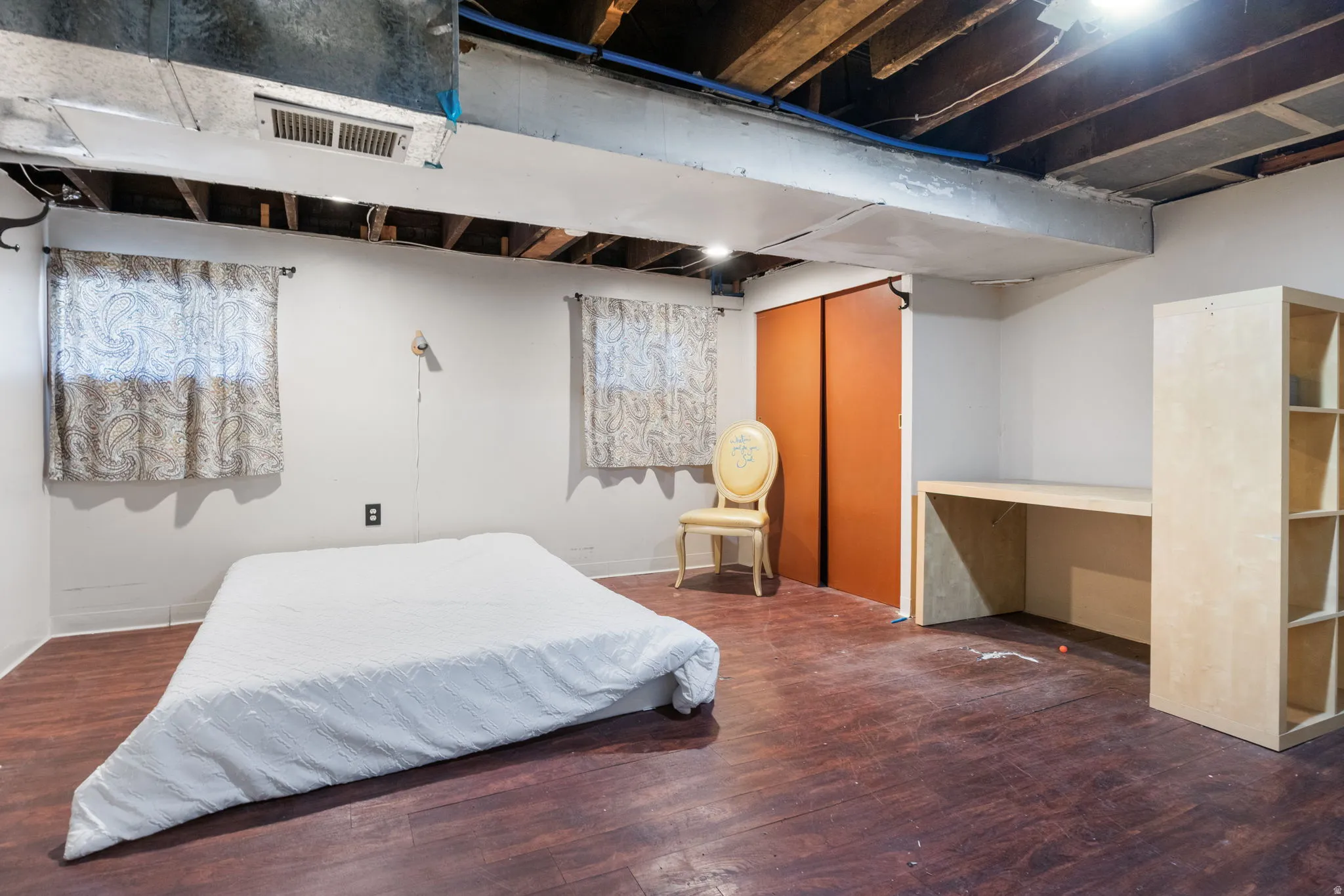Room featuring wood-finish flooring, two window openings, and a built-in desk with shelving