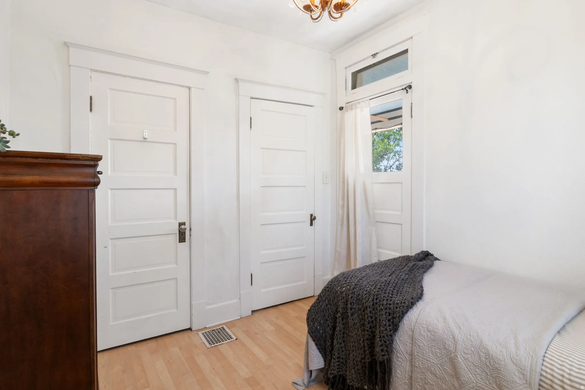 Interior room featuring a ceiling-mounted light fixture, light wood-finish flooring, and white paneled doors
