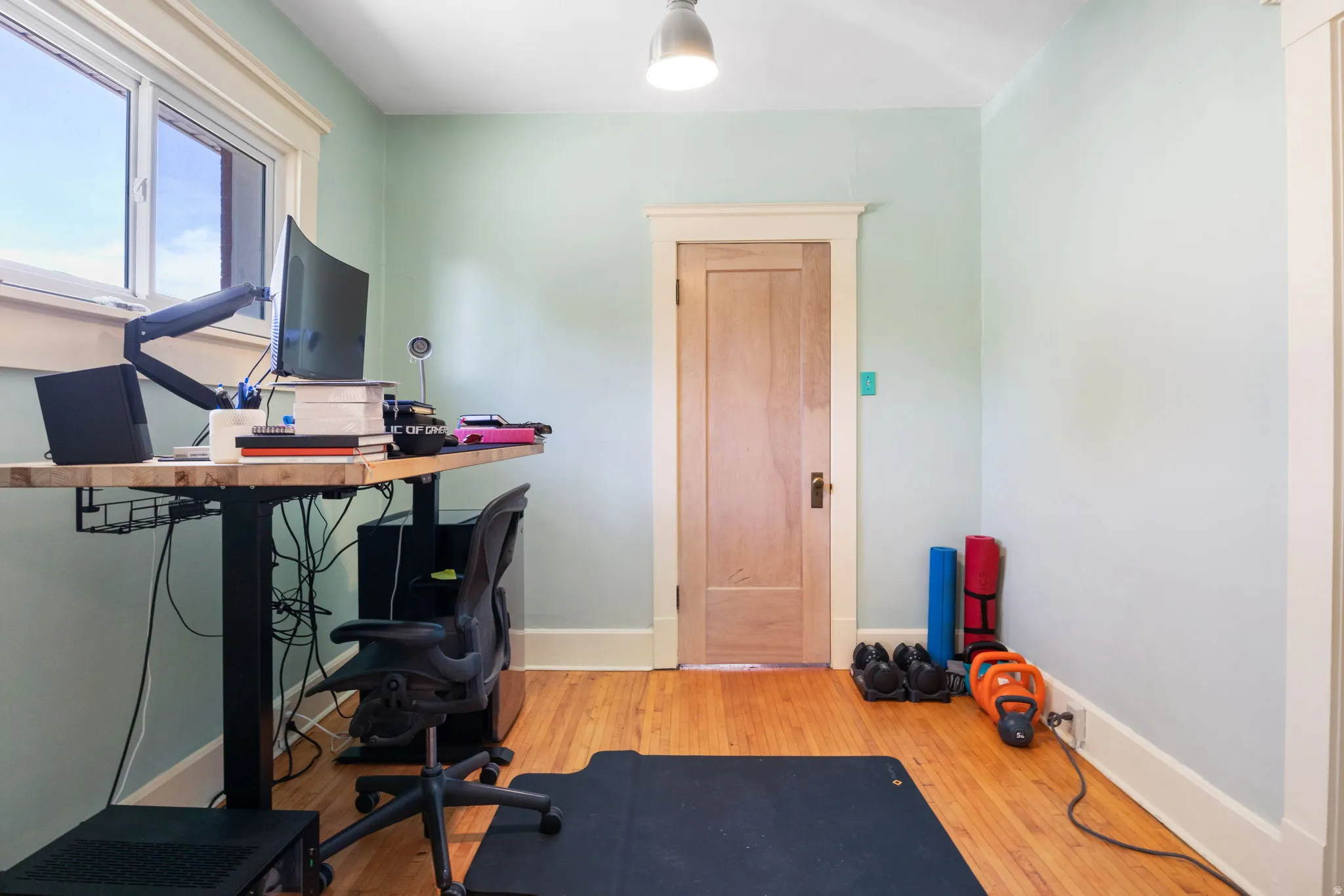 Room featuring wood-finish flooring, a single window with white trim, and light-toned wall paint