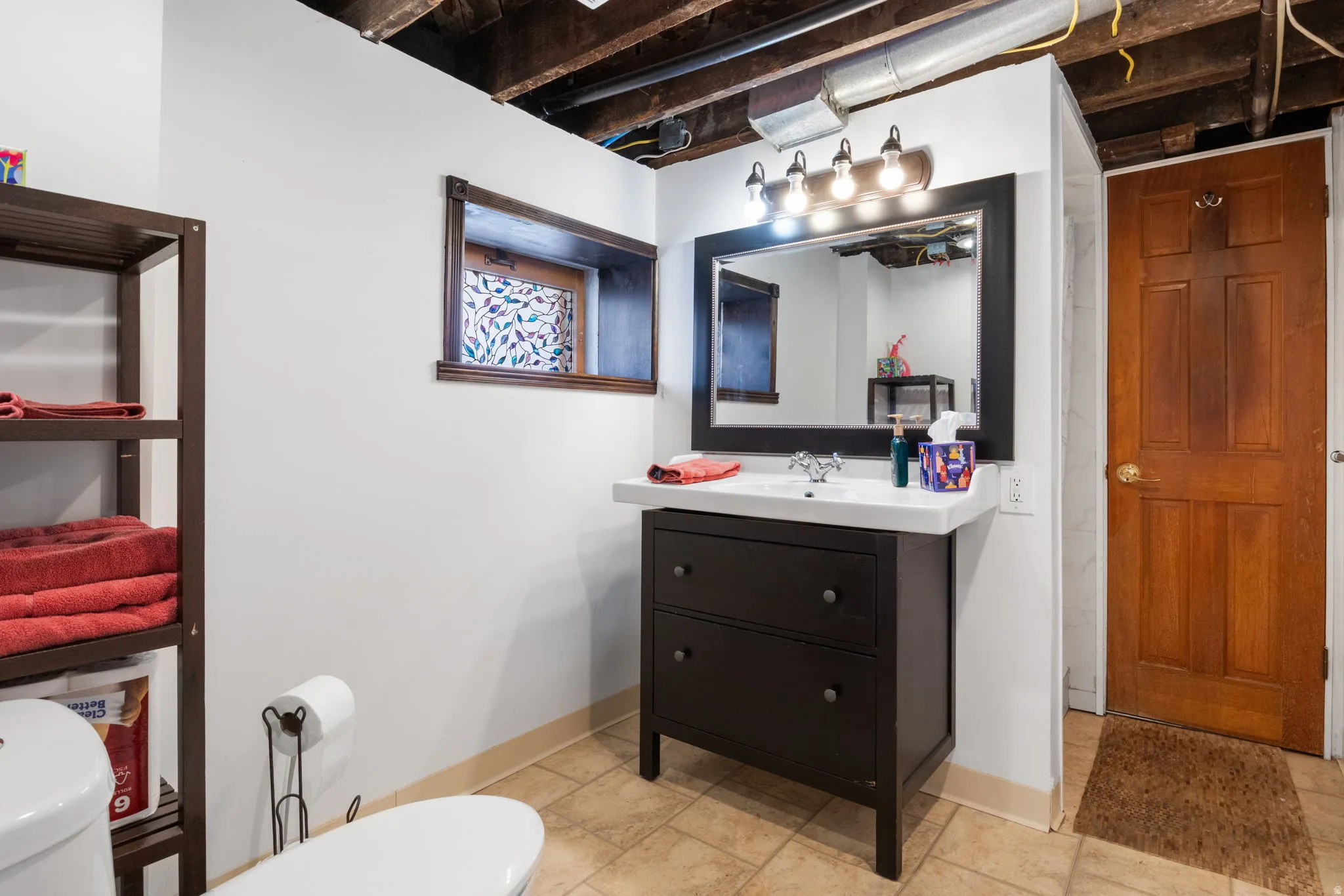 Bathroom vanity with a dark wood-finish cabinet, integrated sink, and wall-mounted mirror
