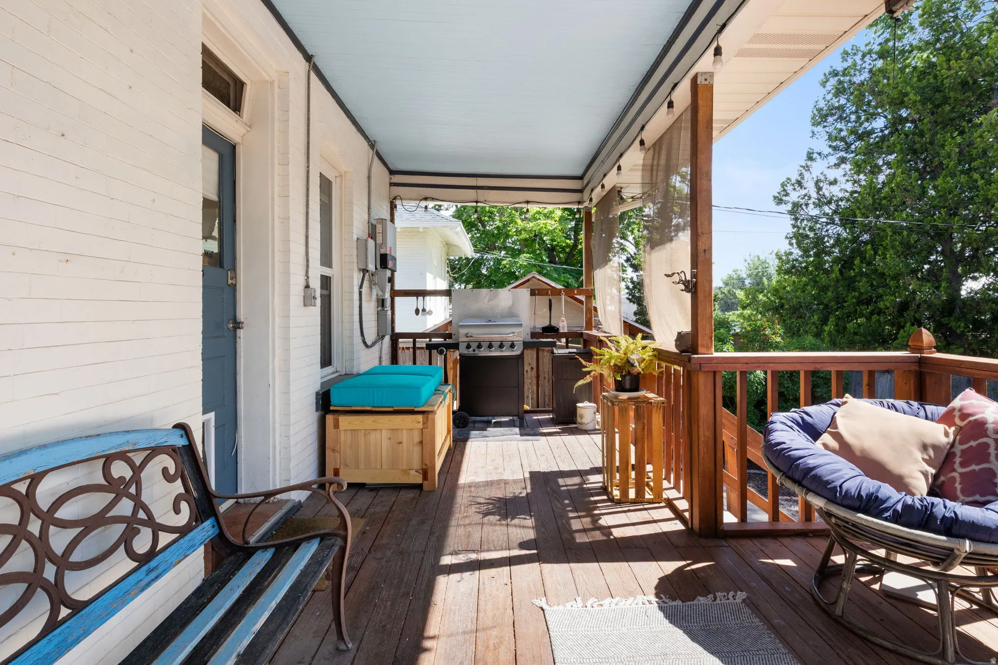 Spacious outdoor deck featuring natural wood flooring and railings, a light blue ceiling, and opaque privacy screens