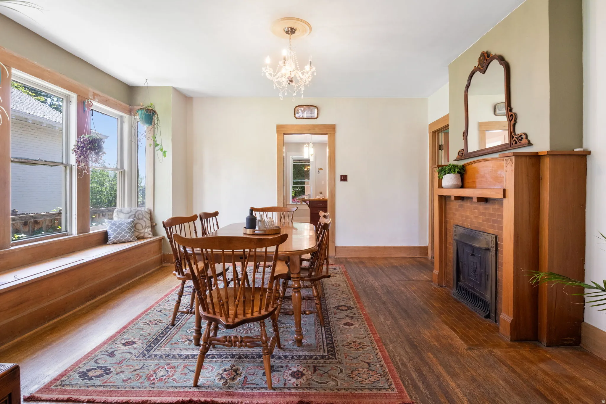 Dining area featuring a wood-finish floor, built-in window bench, and a brick fireplace with a wood mantel