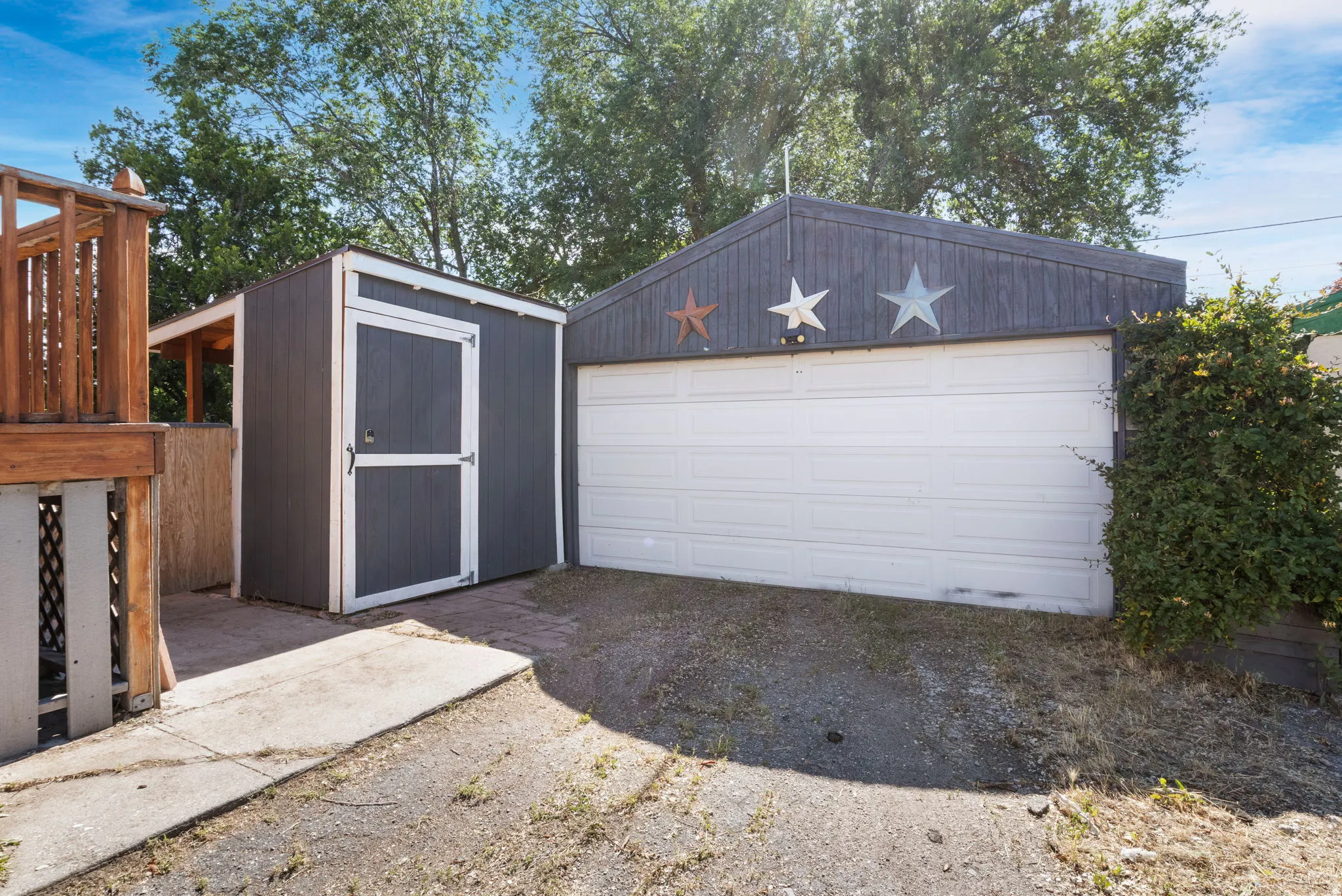 Detached garage with a white panel door and an adjacent storage shed