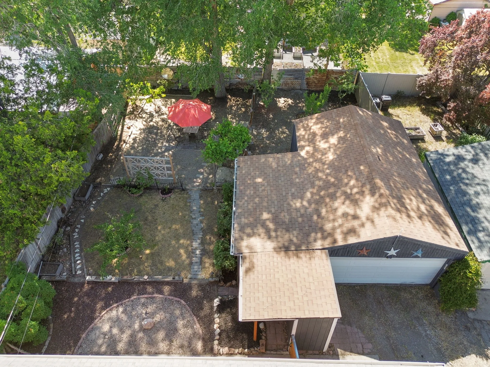 Fenced backyard featuring mature trees, a designated patio area, and stepping stone pathways