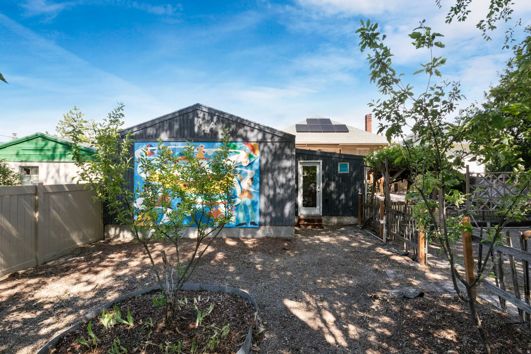 Rear exterior of the property featuring dark vertical siding and a vibrant mural
