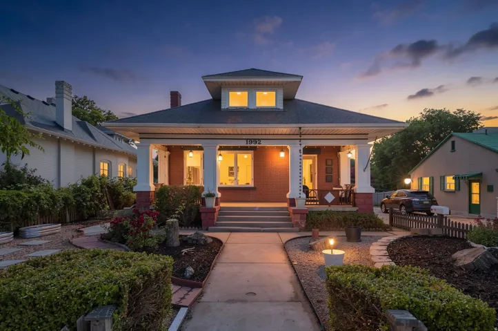 Brick exterior featuring a covered front porch with substantial columns, a pitched roofline, and a dormer