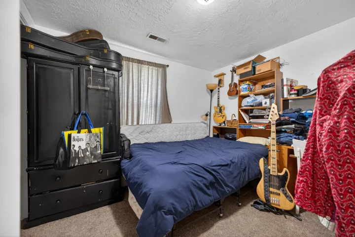 Carpeted room featuring a window with blinds, ceiling-mounted light fixture, and built-in shelving