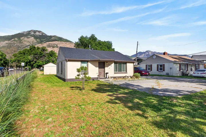 Single-story property with a dark shingle roof, light-colored siding, and a prominent mountain backdrop