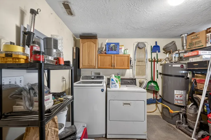 Dedicated utility space featuring overhead cabinetry and a water heater