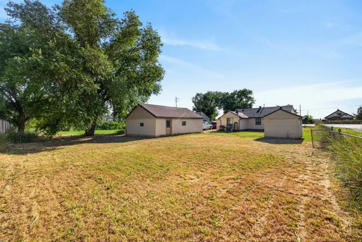 Expansive lot featuring a detached auxiliary building, mature trees, and a rear building with a brown shingle roof