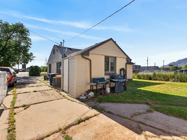 Side yard featuring a concrete driveway, a freestanding storage shed, and a grassy area