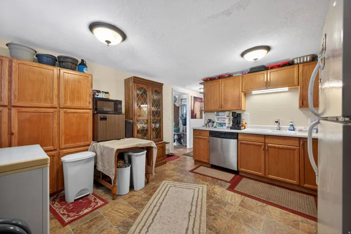 Kitchen featuring wood-finish cabinetry, a white countertop, and stainless steel dishwasher