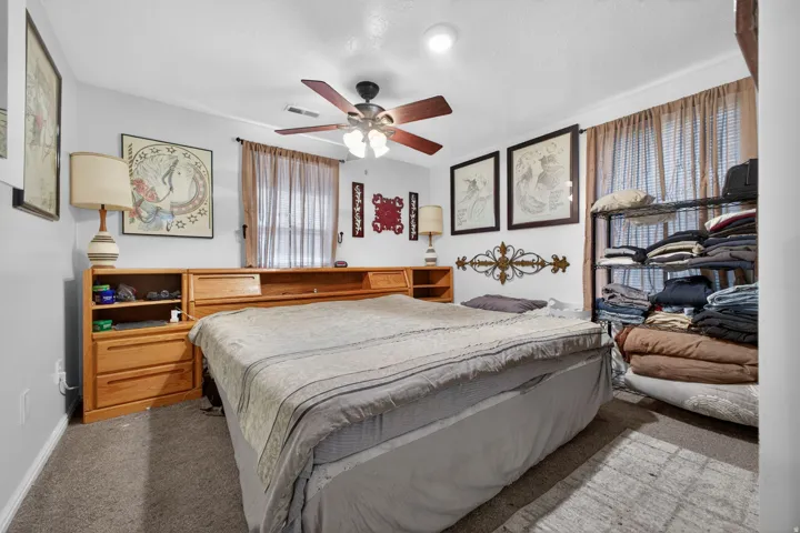 Carpeted bedroom featuring a ceiling fan with integrated lighting, window with horizontal blinds, and light-toned wall finishes