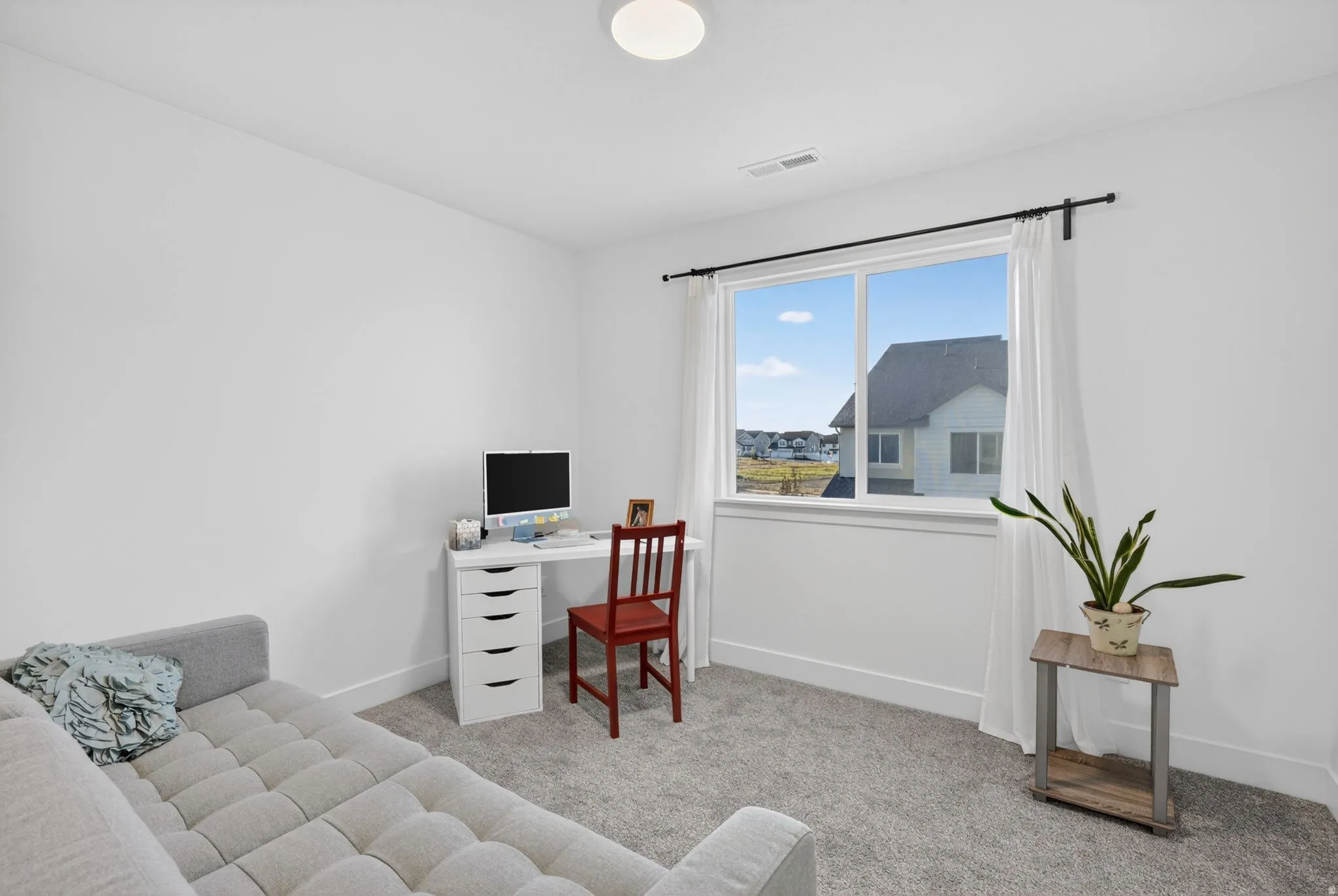 Bright room featuring a large window, white trim, and neutral carpeting