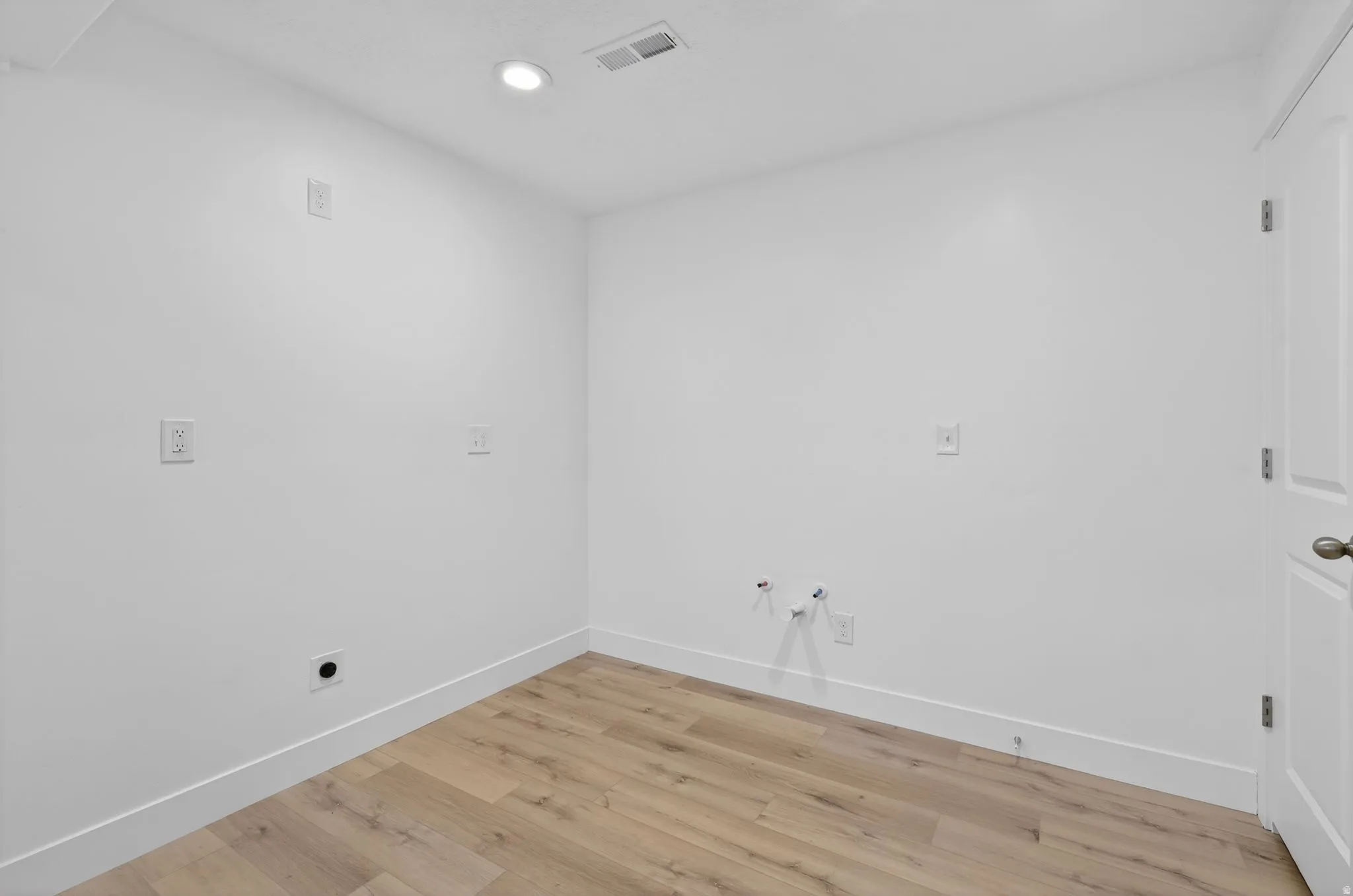 Utility space featuring wood-finish flooring, white walls, and a recessed ceiling light