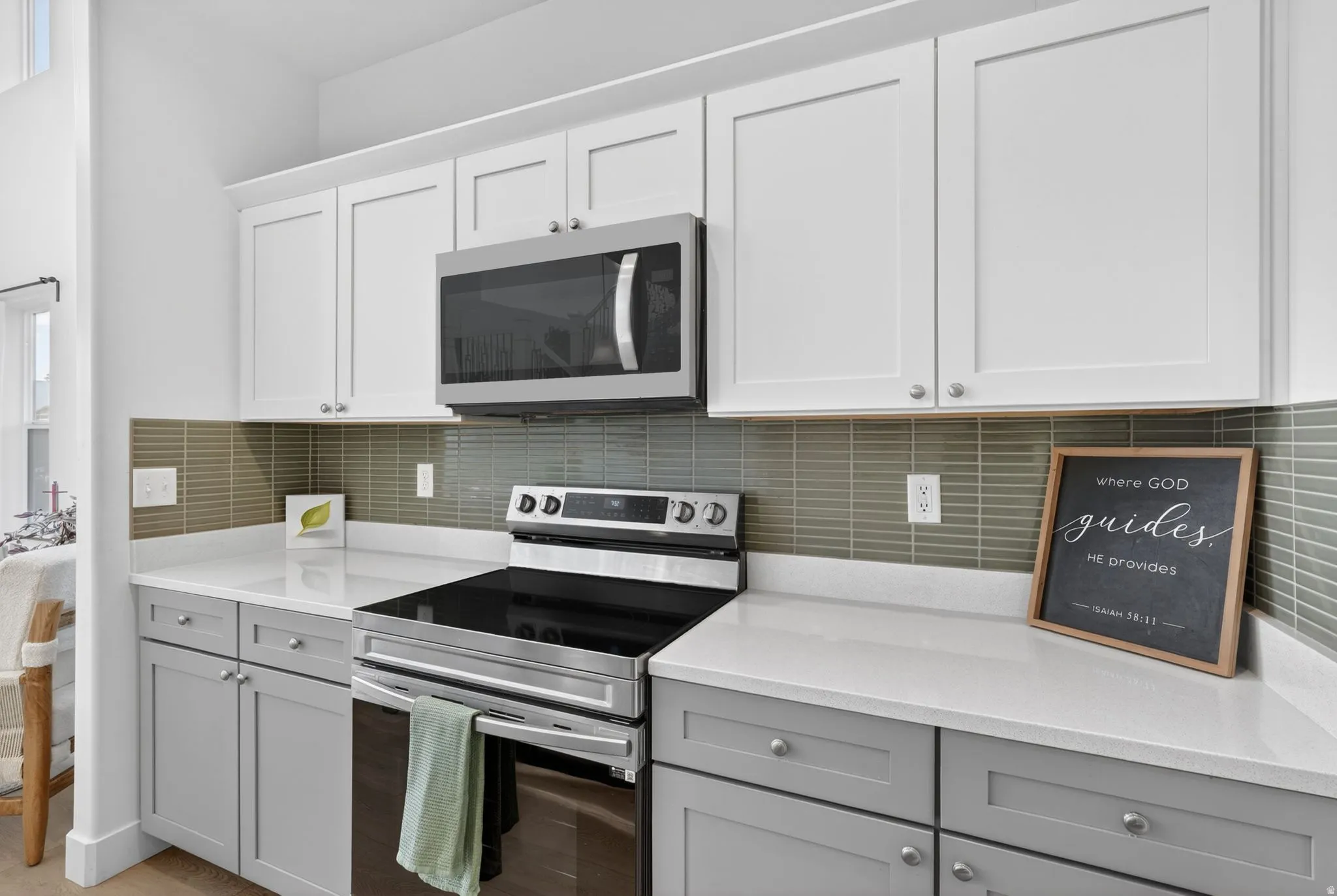 Modern kitchen featuring white upper cabinetry, gray lower cabinetry, and a subway tile backsplash