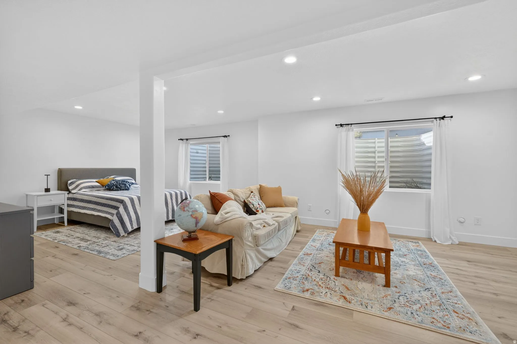 Bright open-concept living area featuring wood-finish flooring, recessed lighting, and crisp white walls