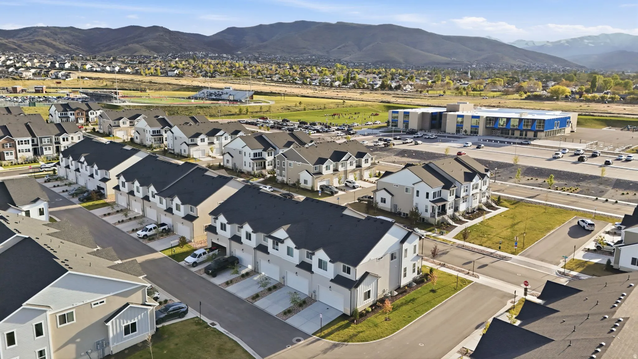 Row of residential townhomes featuring multi-story facades with light-colored siding and dark shingle roofs