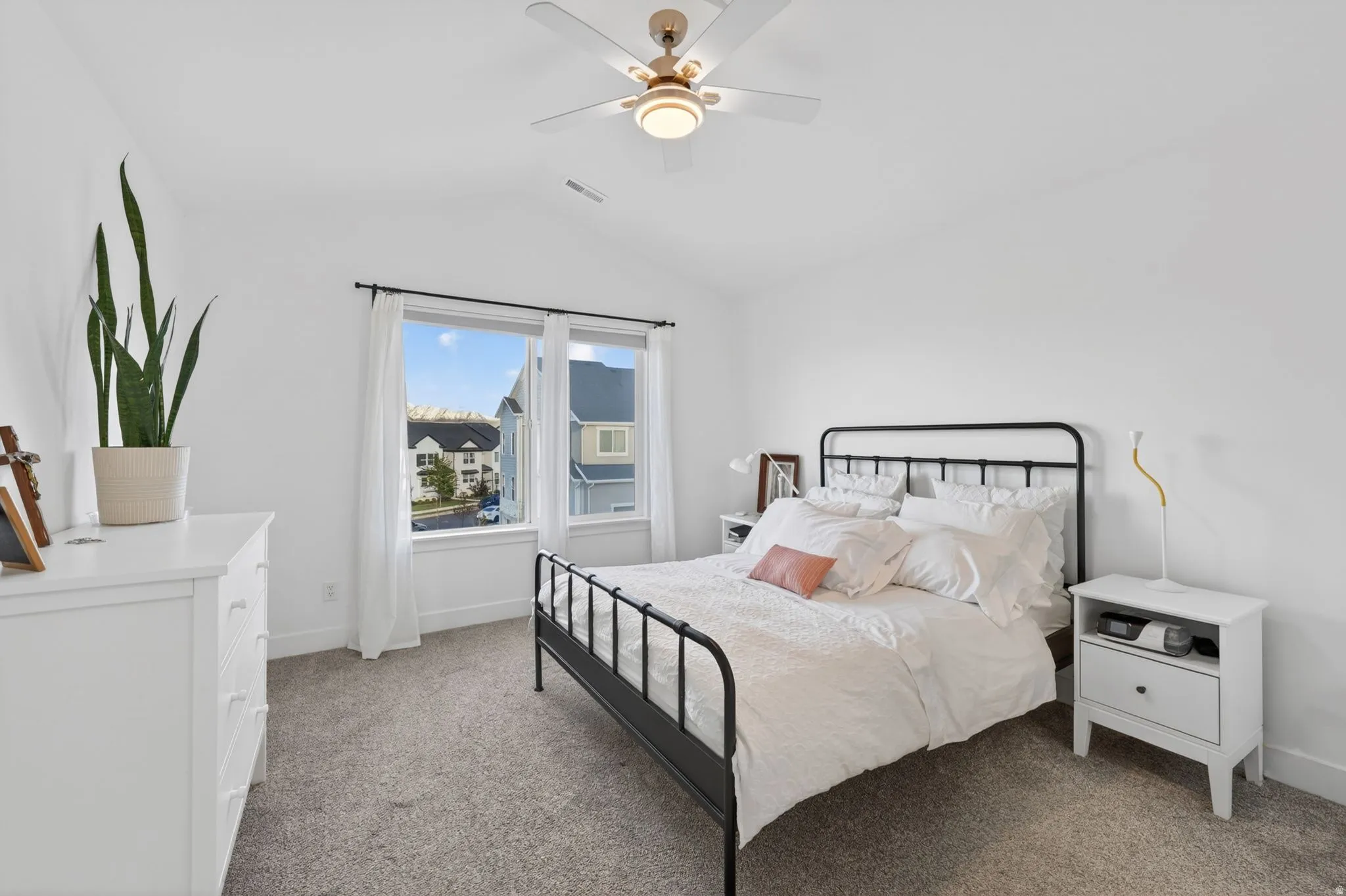 Bright room featuring white walls, a multi-pane window with black trim, and light-colored carpet flooring