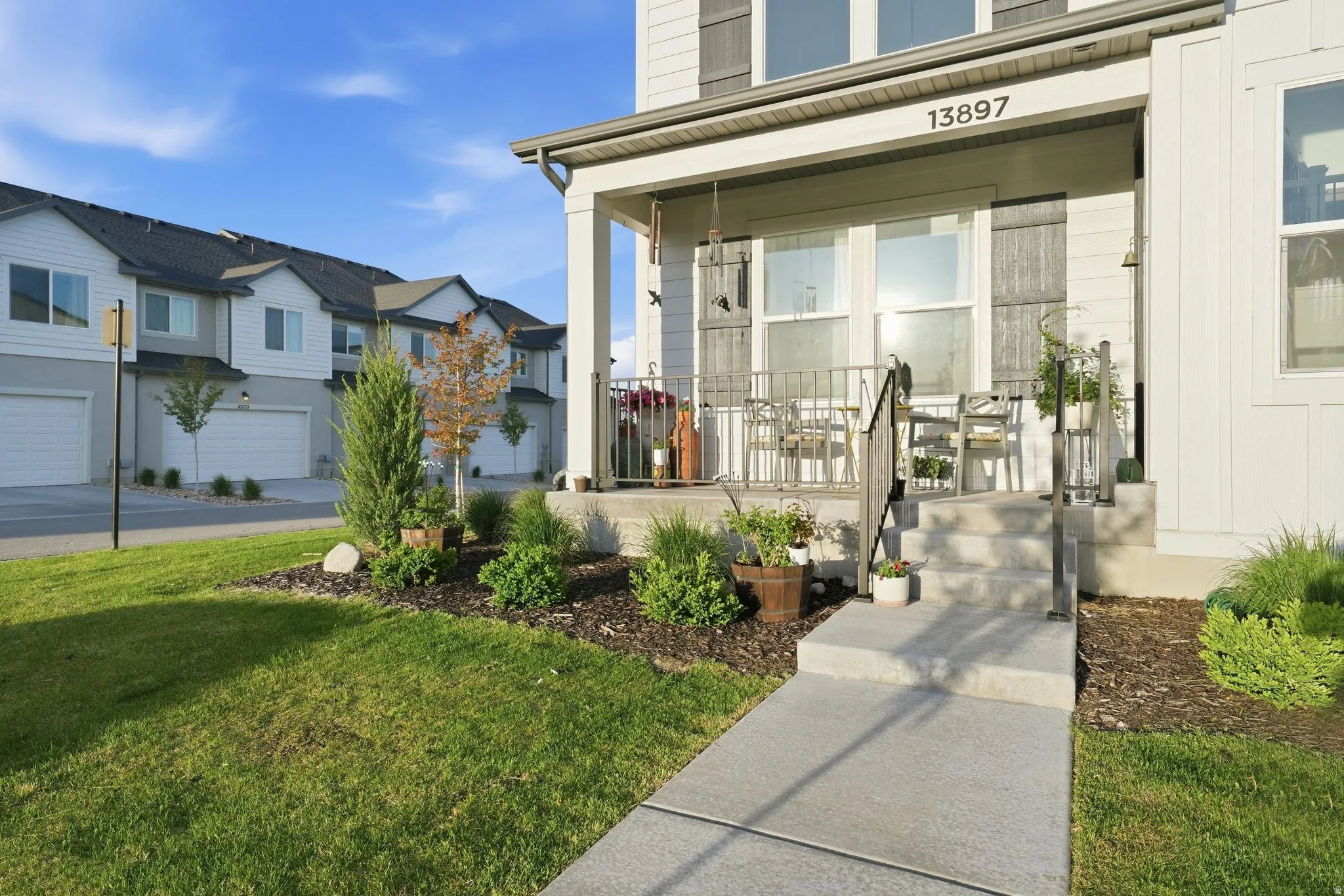 Covered front porch with concrete steps and metal railings