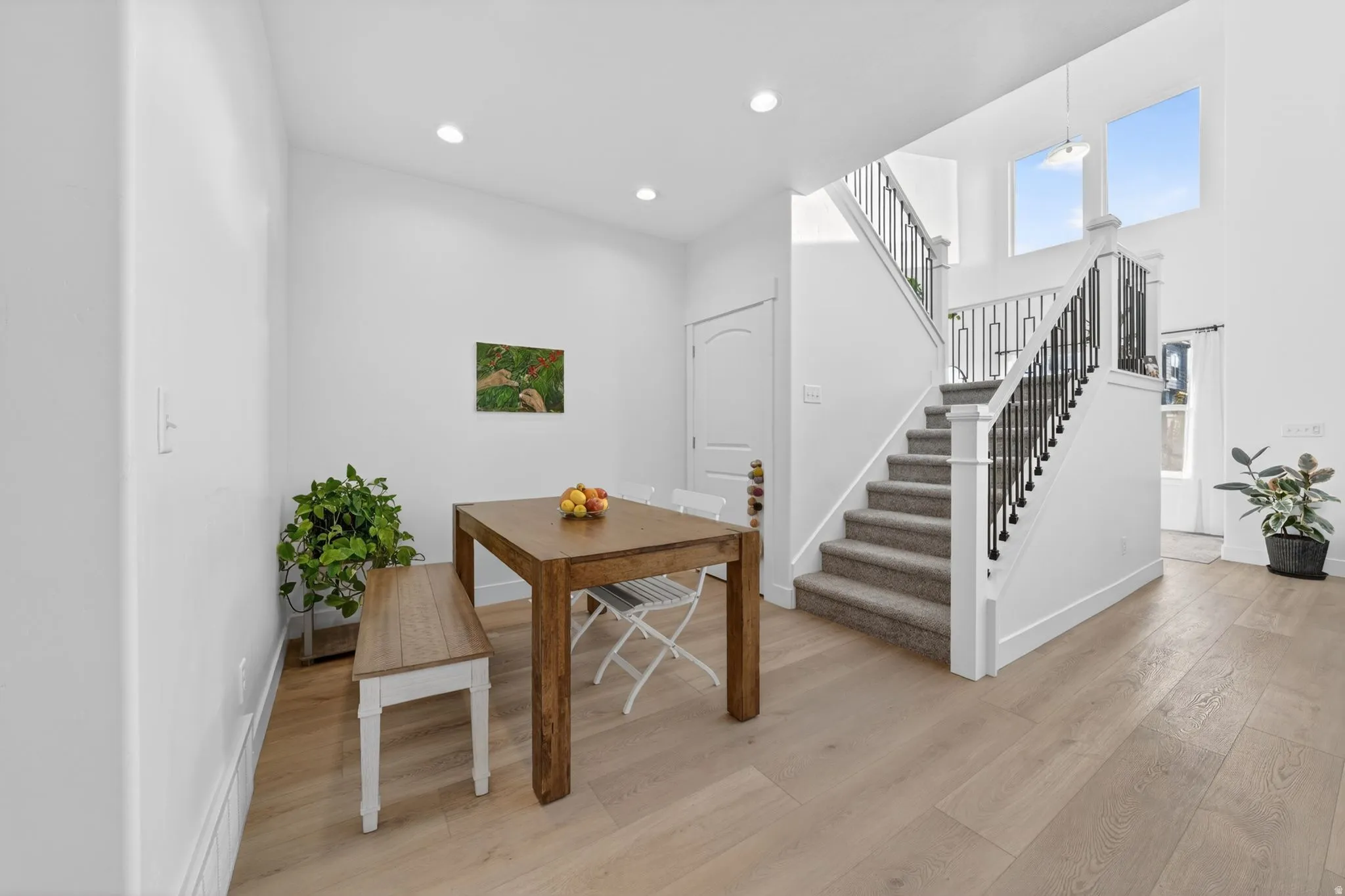 Light wood-finish flooring extending into a spacious entryway with a carpeted staircase