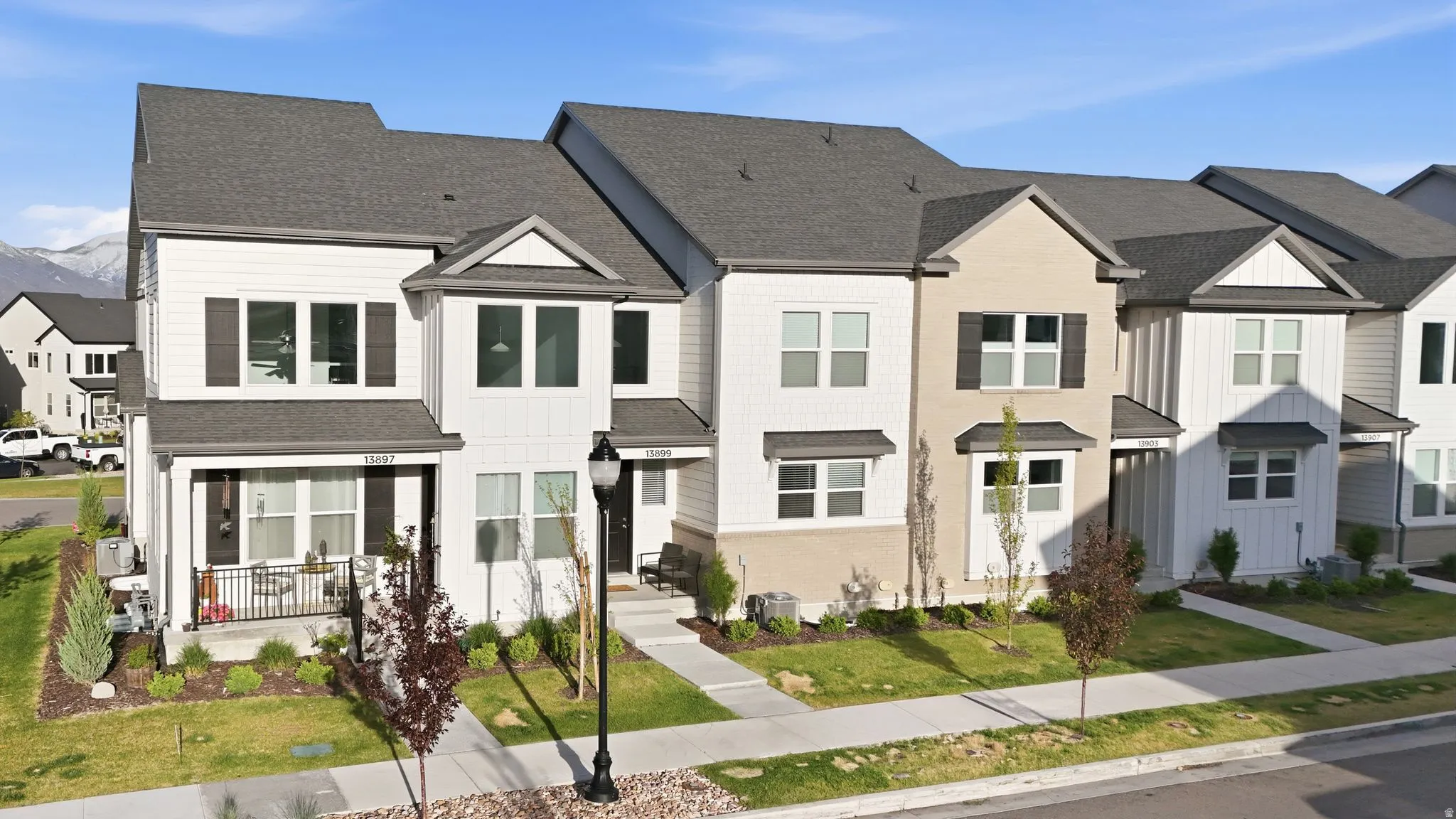 Contemporary townhome featuring a multi-textured facade with white siding, light beige stucco, and dark gray shingle roofing