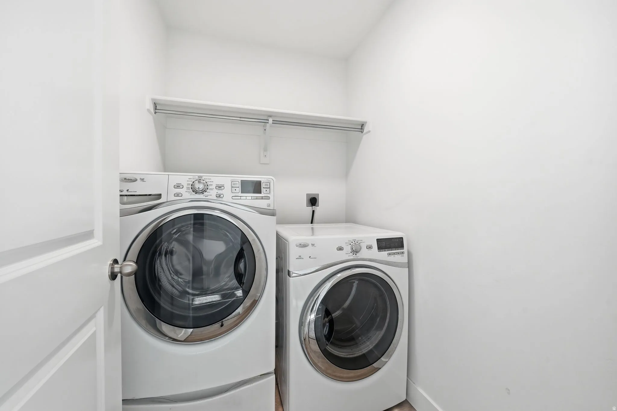 Dedicated laundry space featuring white walls, a built-in shelving unit, and wood-finish flooring
