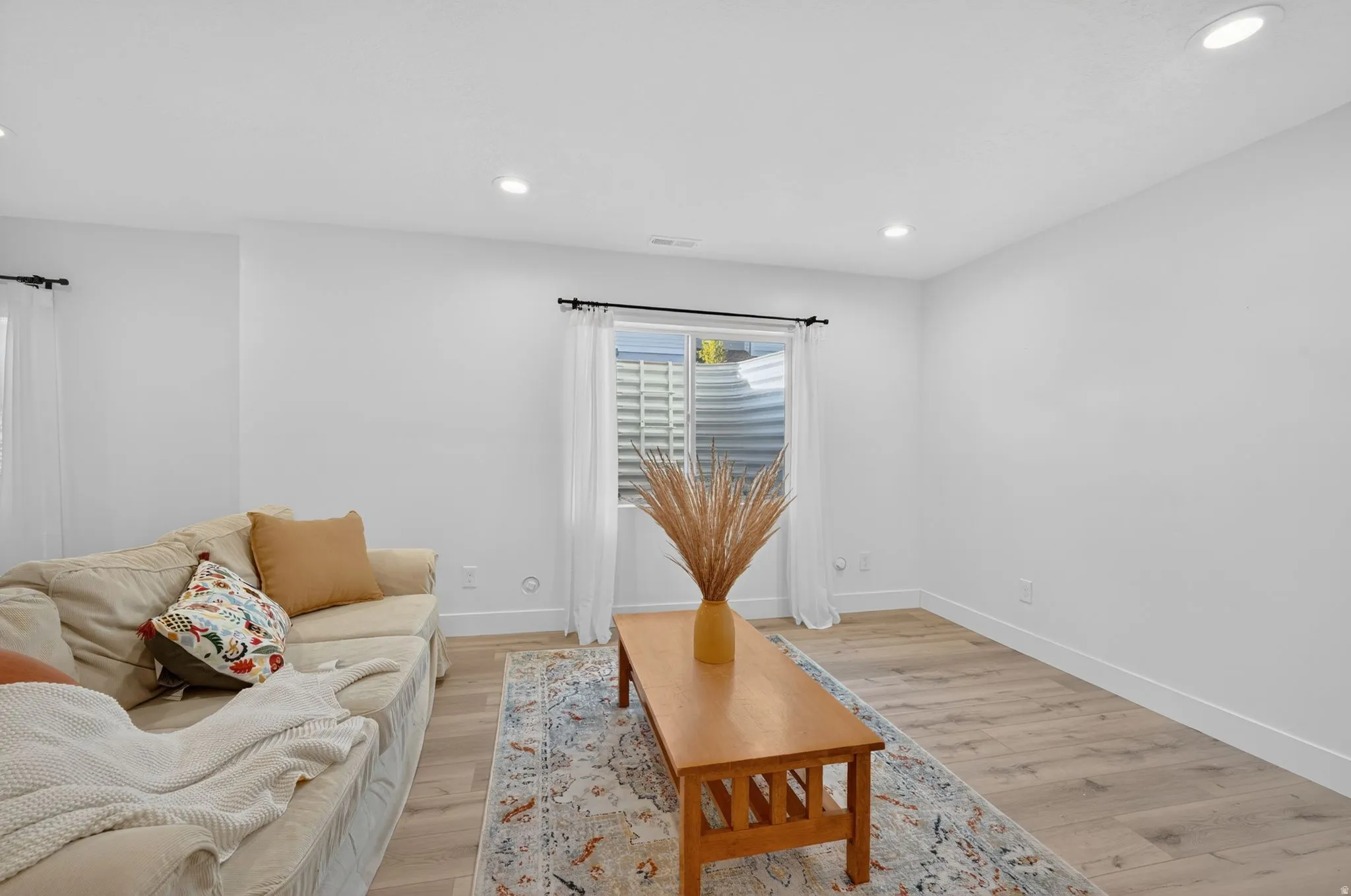 Spacious room featuring light wood-finish flooring, recessed lighting, and a window with a window well