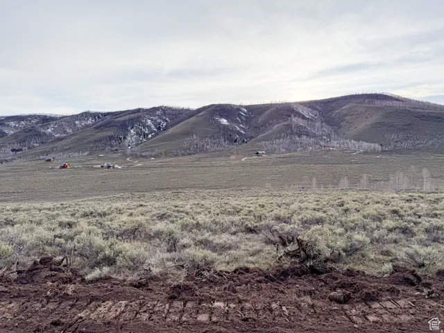 Expansive high desert landscape featuring rolling hills and distant snow-dusted mountains